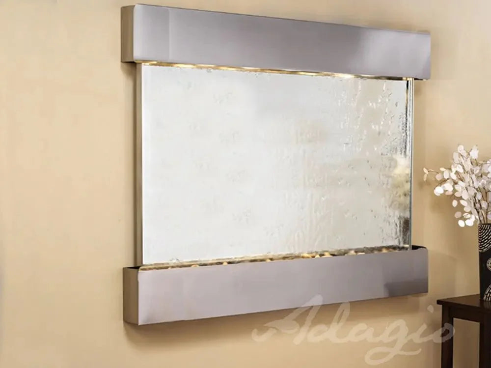 Wall-mounted water feature with metallic frame on a beige wall, brand 'Adagio' visible.