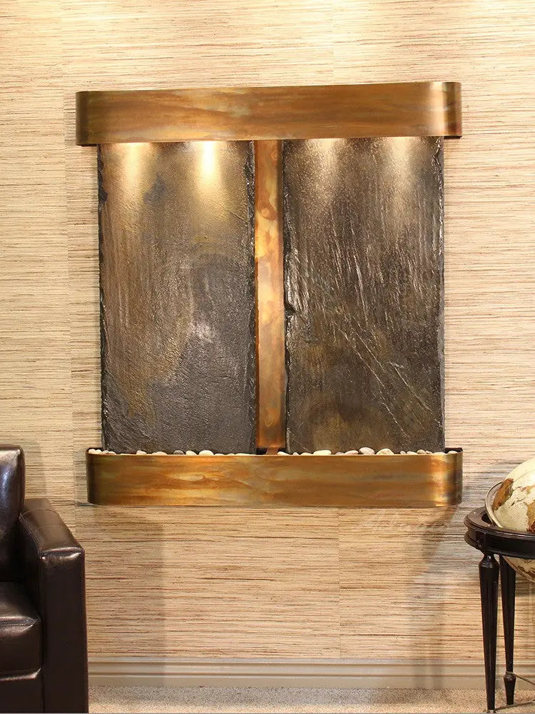Wall-mounted water feature with bronze and stone design against a textured wall.