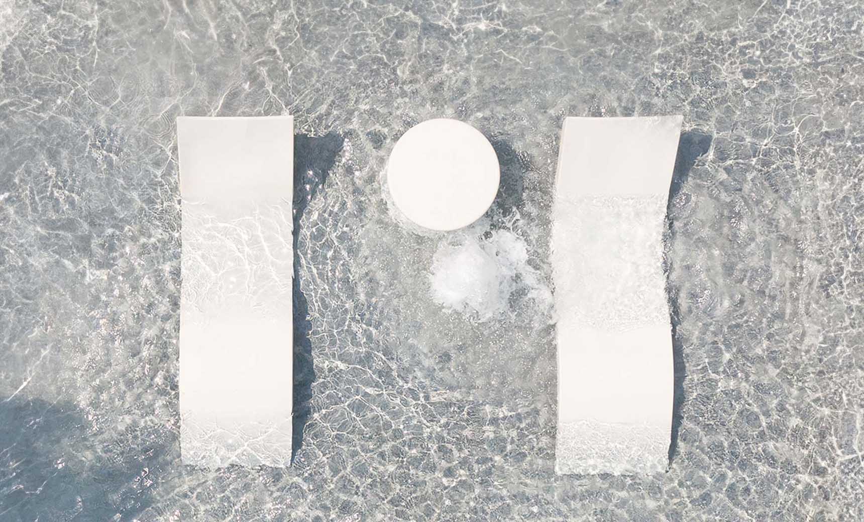 Signature chaise lounge in pool with matching deep cushion and side table for relaxation.