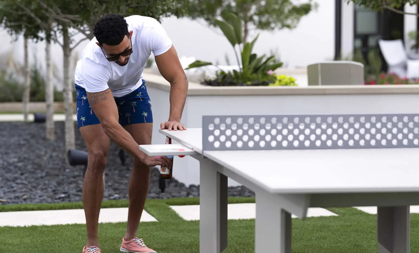 Table tennis table with green playing surface and two barstools placed nearby.
