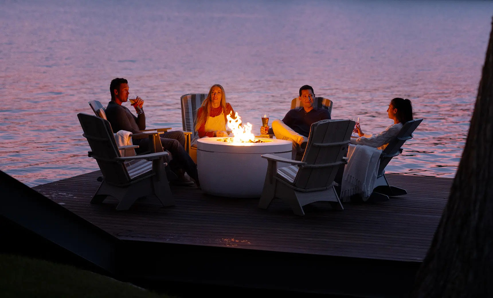 Halo Firepit surrounded by four Adirondack chairs in wooden tones and green cushions.