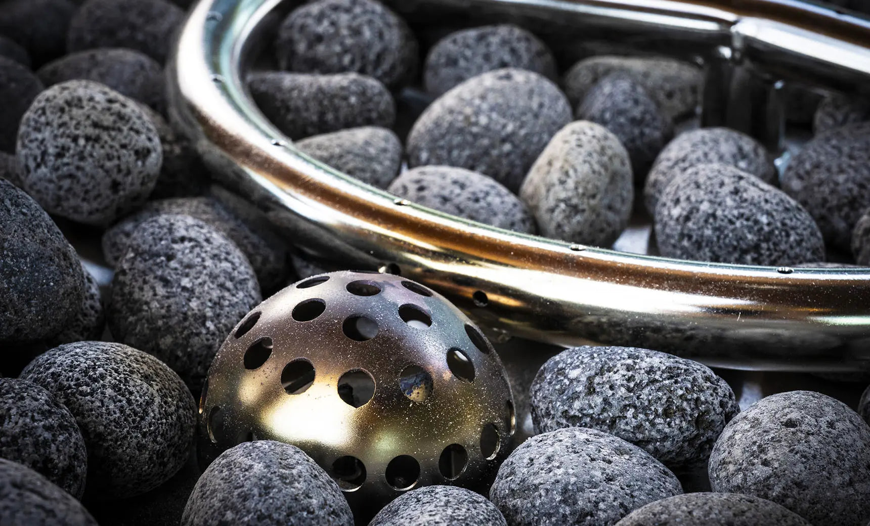 Halo firepit with a black steel frame and glass bowl containing rocks and logs.