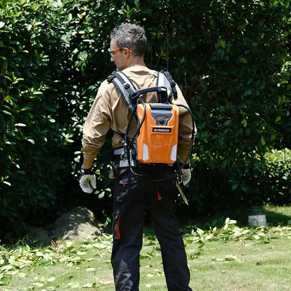 Man using a backpack leaf blower in a garden setting