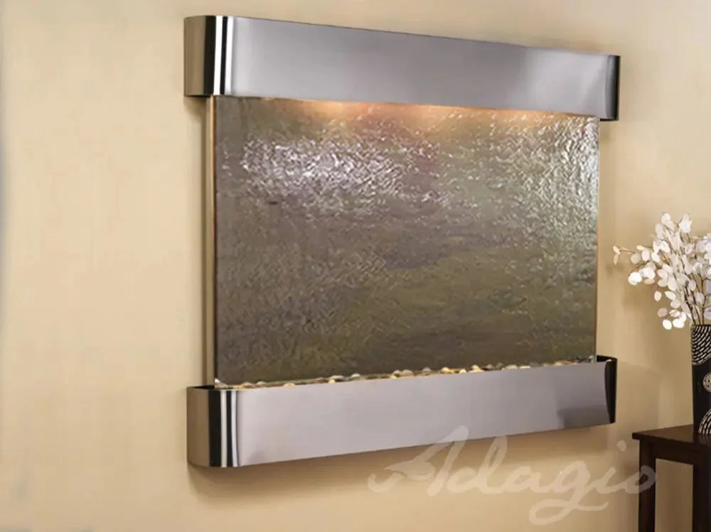 Wall-mounted water feature with metallic finish on a beige wall, Adagio brand visible.