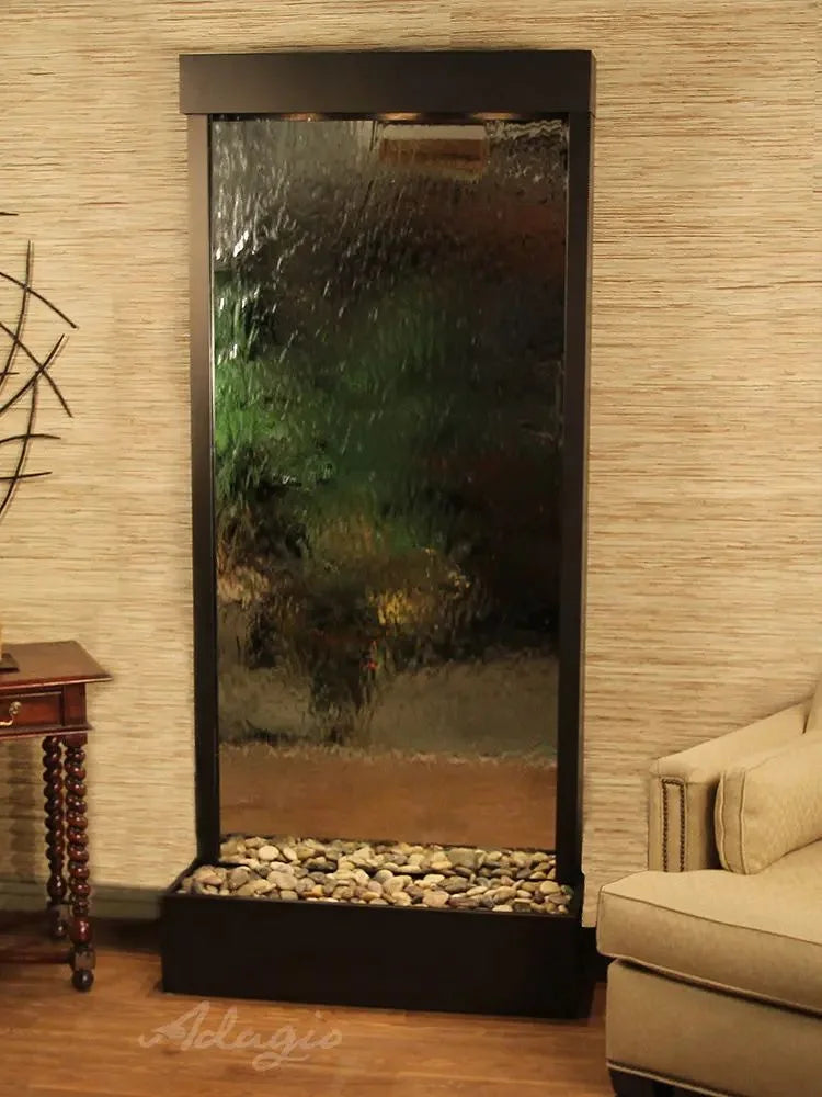 Faux water wall feature with rocks and glass in a room setting, brand 'Adego' visible.