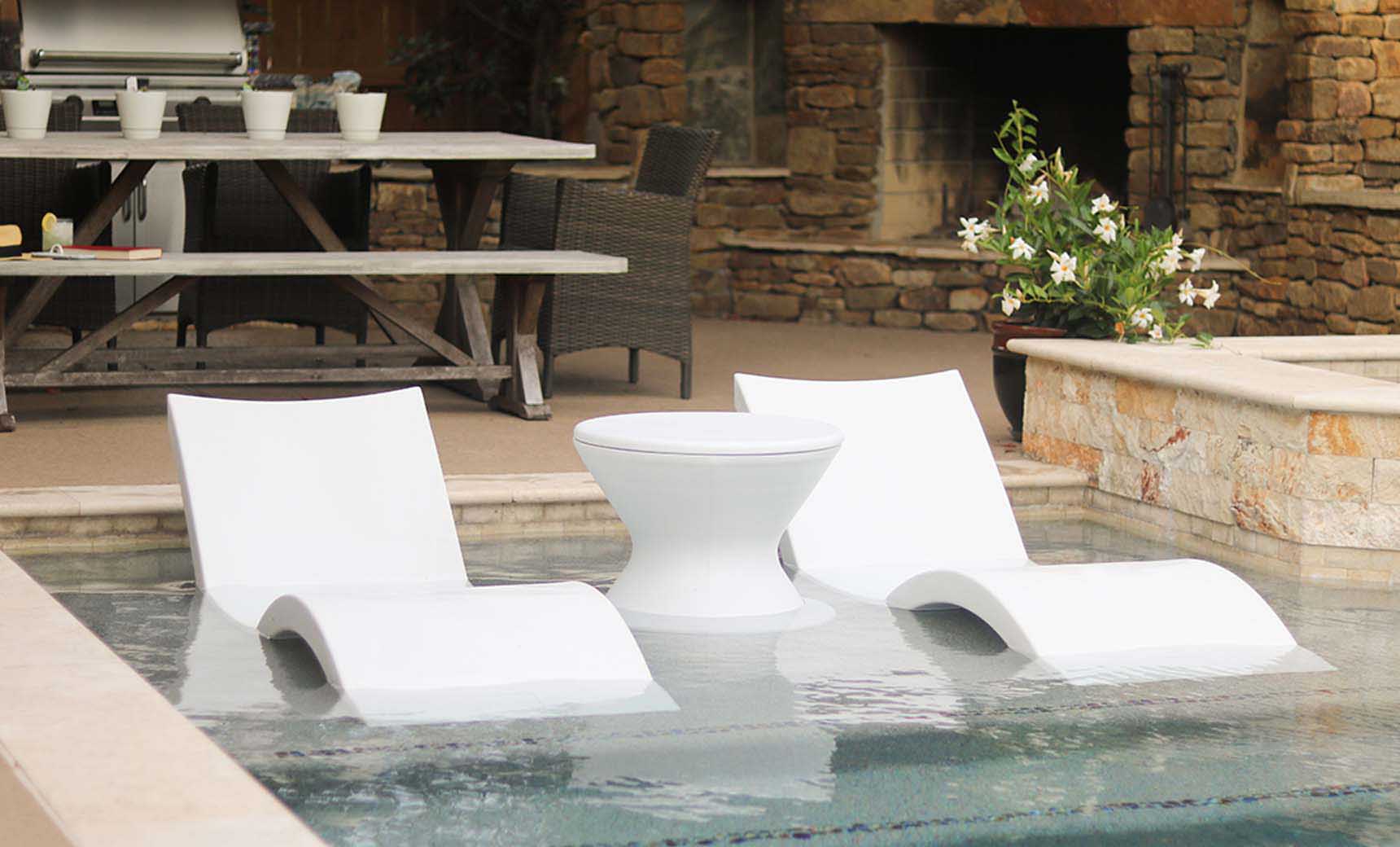 Signature Chaise lounge in pool with matching deep cushion and side table for relaxation.