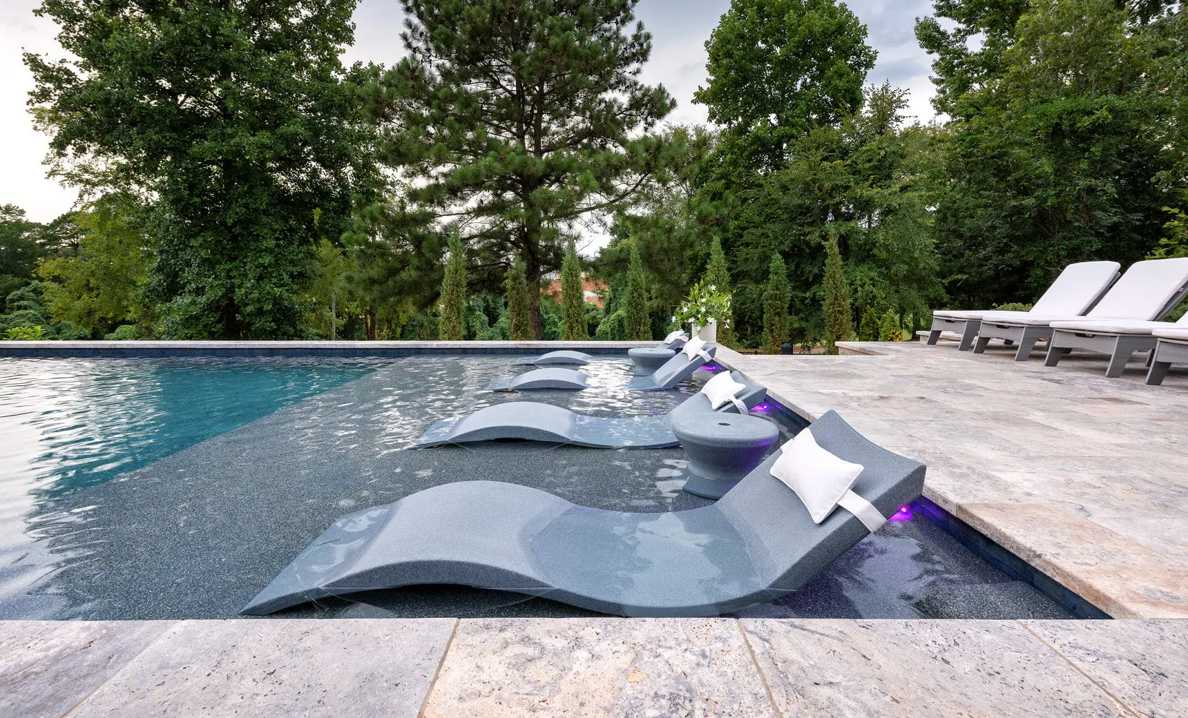 Signature chaise headrest pillow paired with a side table for in-pool use, both in a modern design.