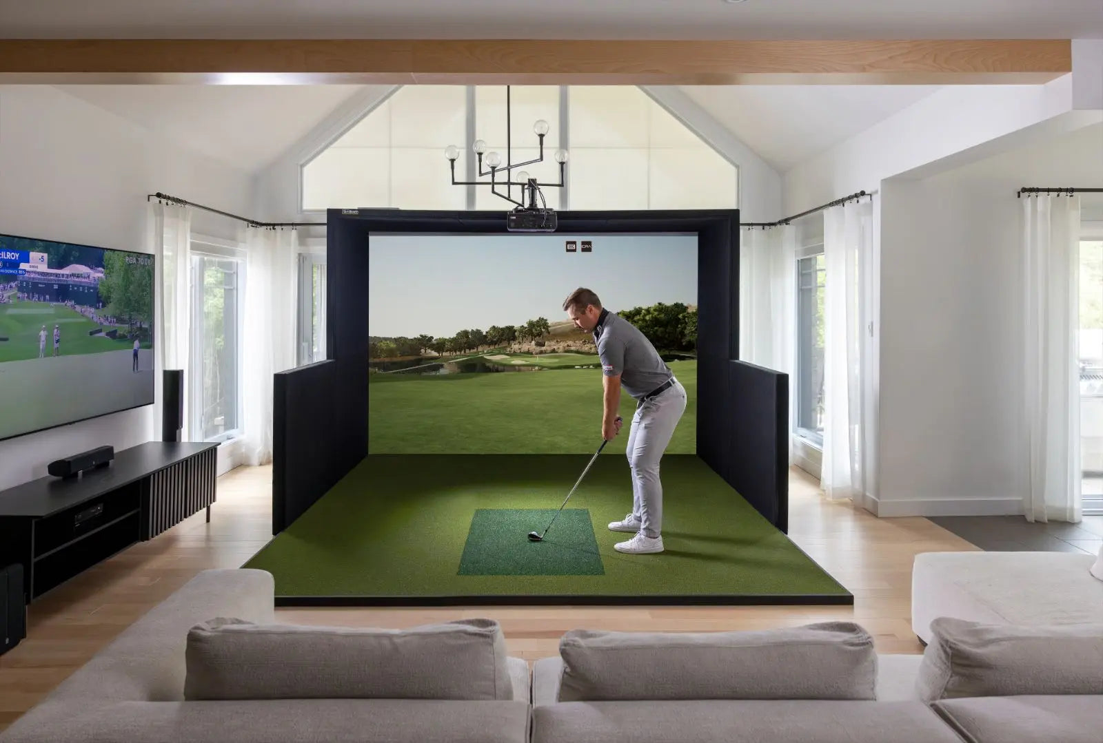 Man playing golf on a virtual simulator in a modern living room.